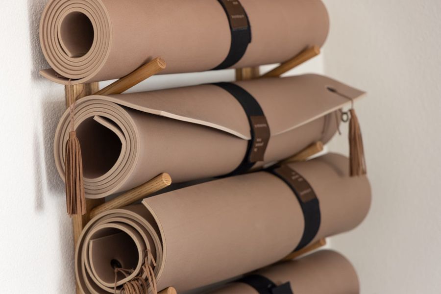 Aufgerollte Yogamatten an einer Wandhalterung aus Holz